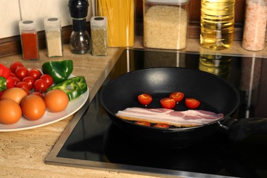 Photo of Cooking bacon with tomatoes in frying pan. Ingredients for breakfast