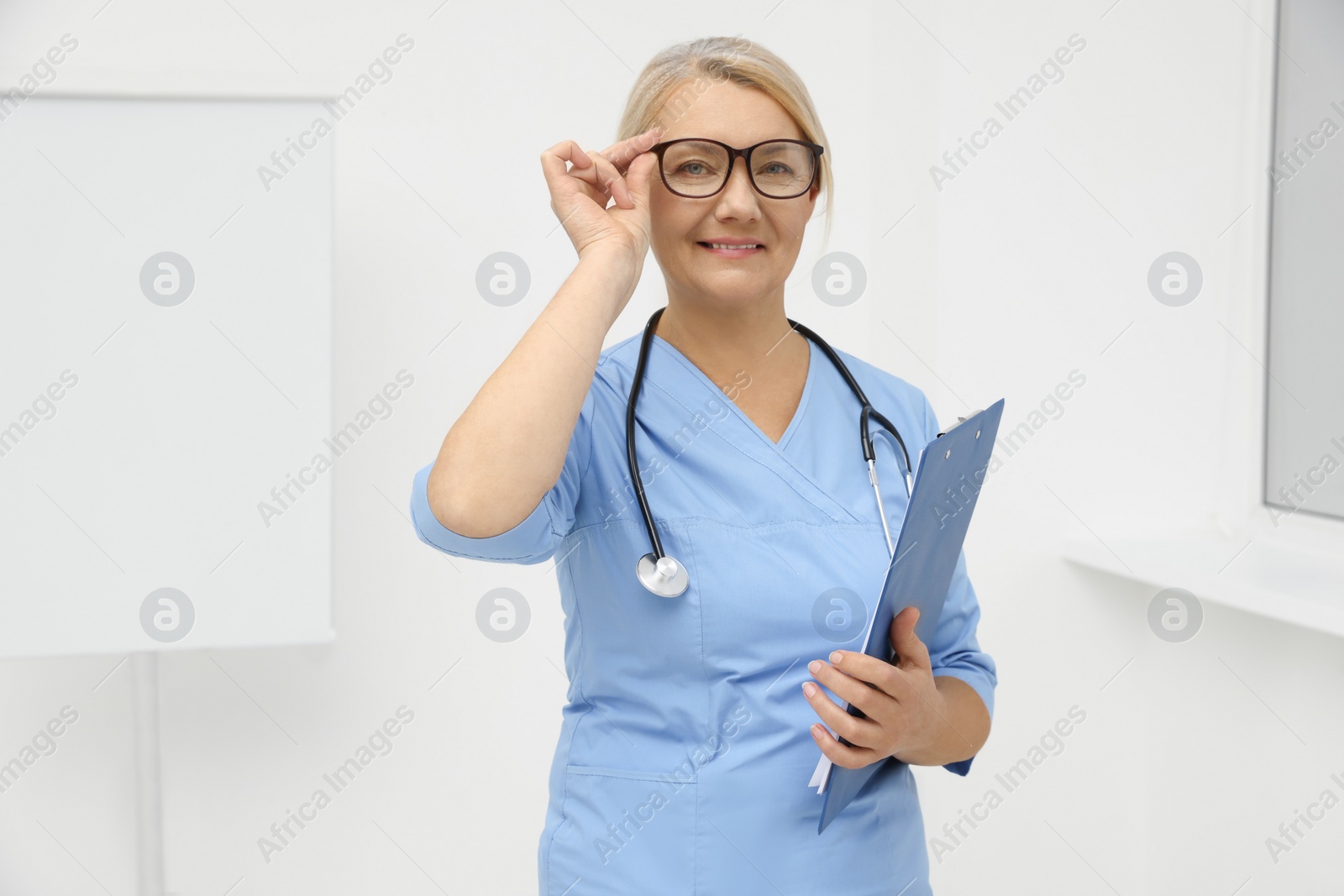 Photo of Professional doctor wearing uniform near flipchart in clinic