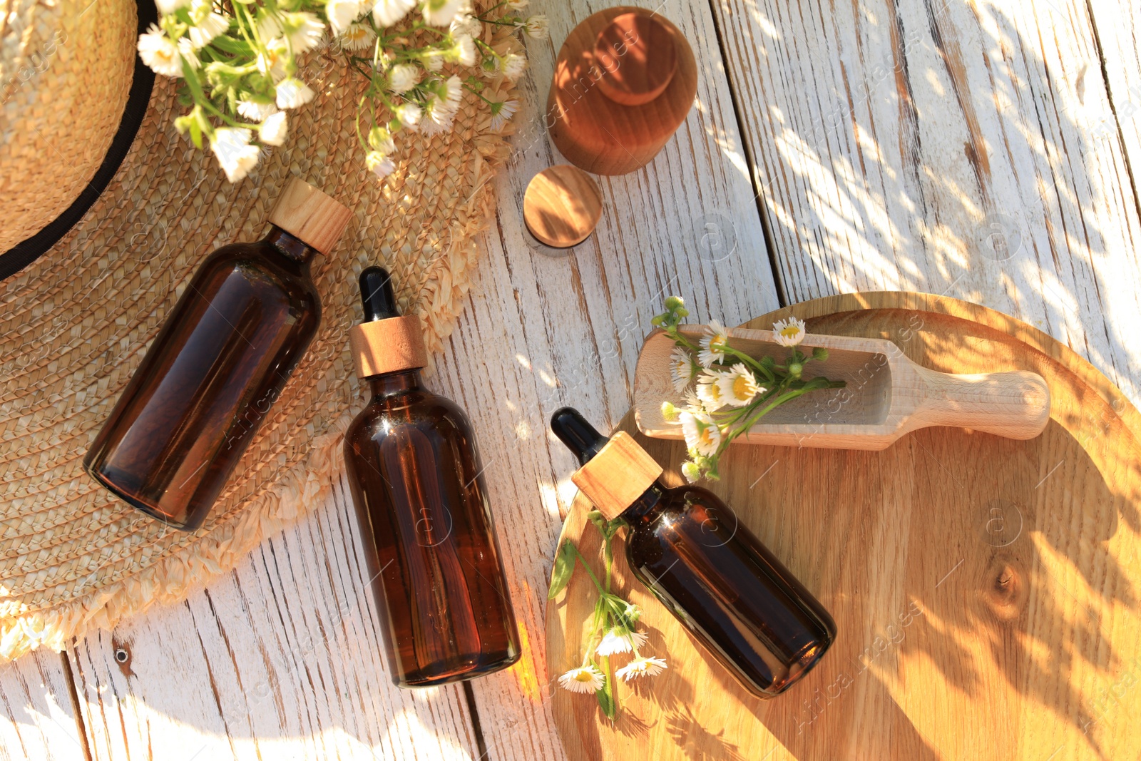 Photo of Flat lay composition with chamomile essential oil and flowers on white wooden table