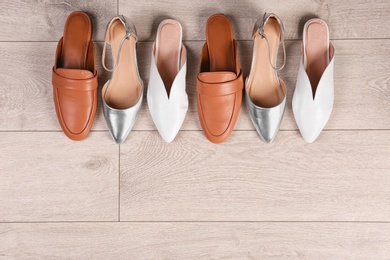 Photo of Different female shoes on wooden background, top view