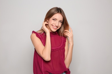 Photo of Portrait of beautiful smiling woman in stylish clothes on light background