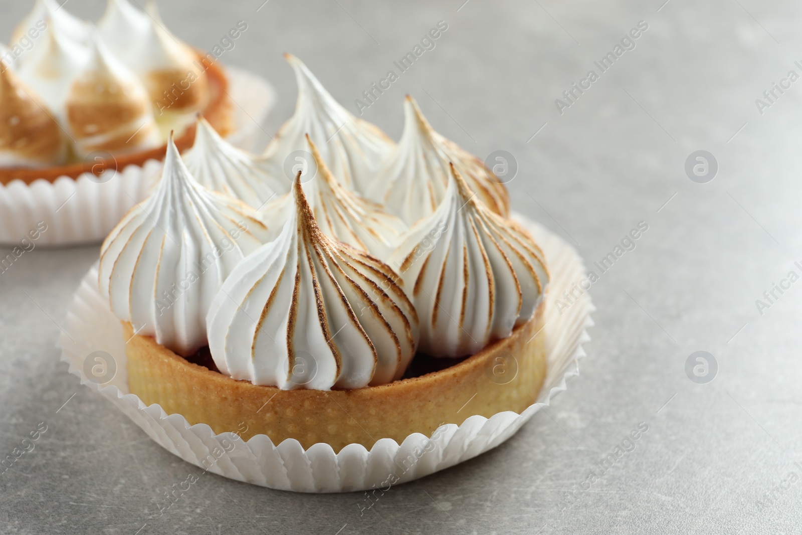Photo of Delicious dessert. Tartlets with meringue on light grey table, closeup