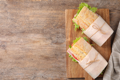 Photo of Tasty sandwiches with ham on wooden table, top view. Space for text