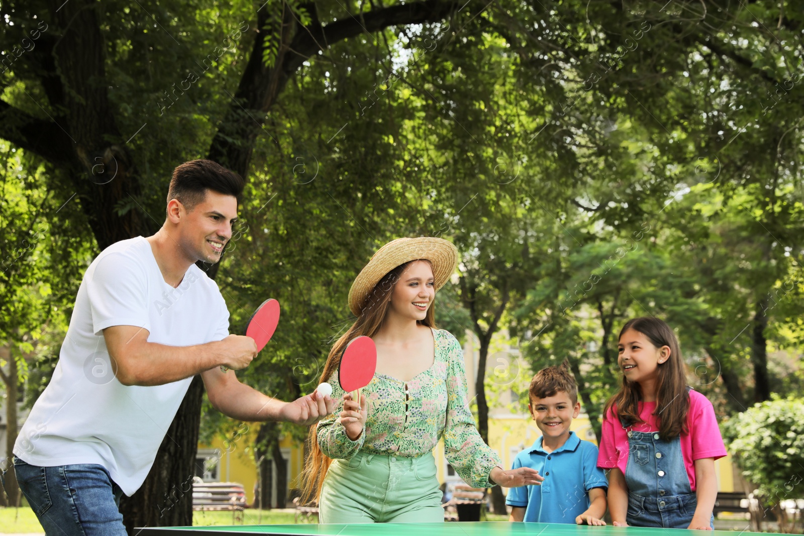 Photo of Happy family playing ping pong in park