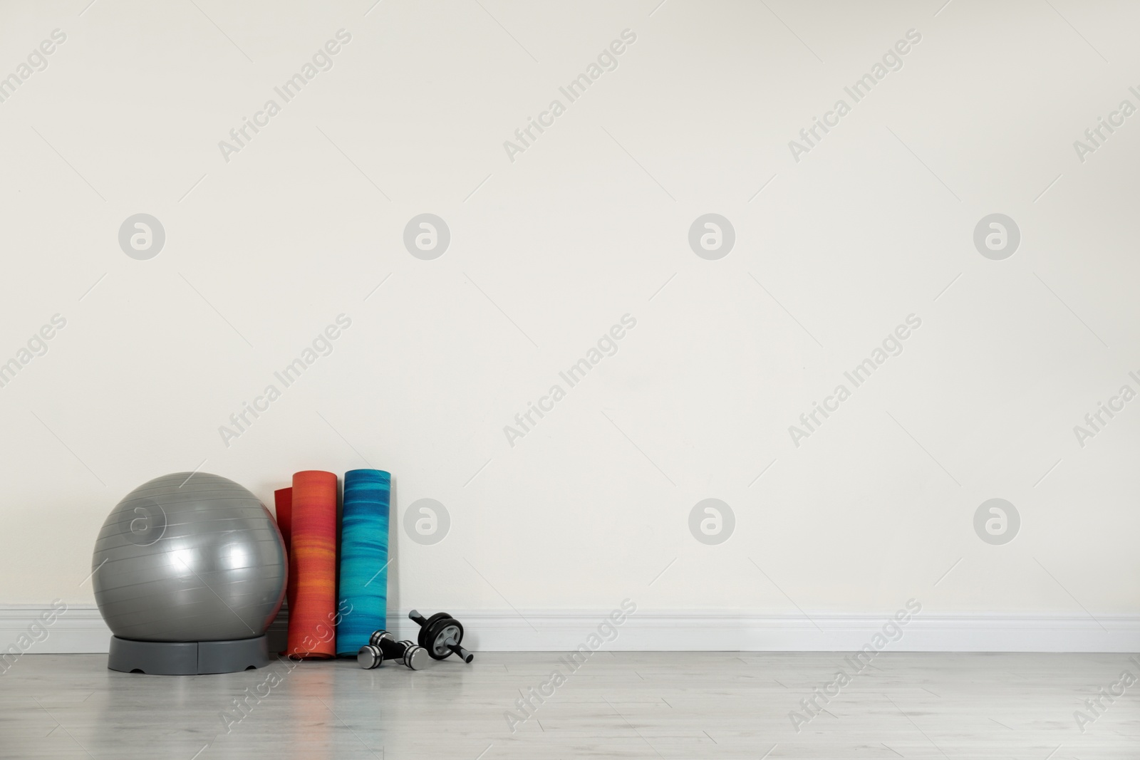 Photo of Set of fitness inventory on floor near white wall, space for text. Rehabilitation medicine