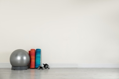 Photo of Set of fitness inventory on floor near white wall, space for text. Rehabilitation medicine