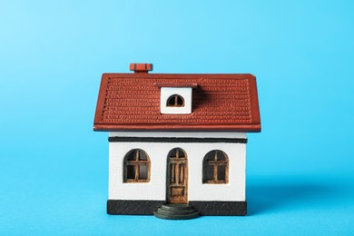 Photo of House model on light blue background. Housewarming party