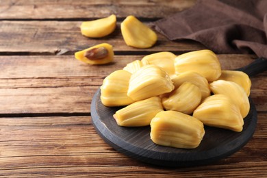 Photo of Delicious exotic jackfruit bulbs on wooden table