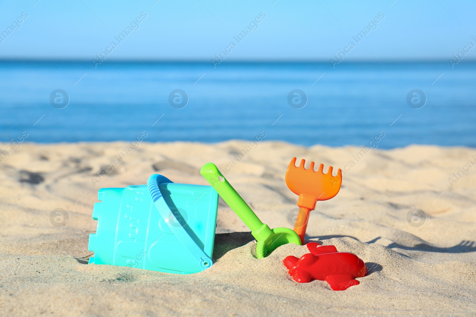 Photo of Set of plastic beach toys on sand near sea