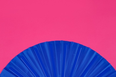 Photo of Blue hand fan on pink background, top view. Space for text