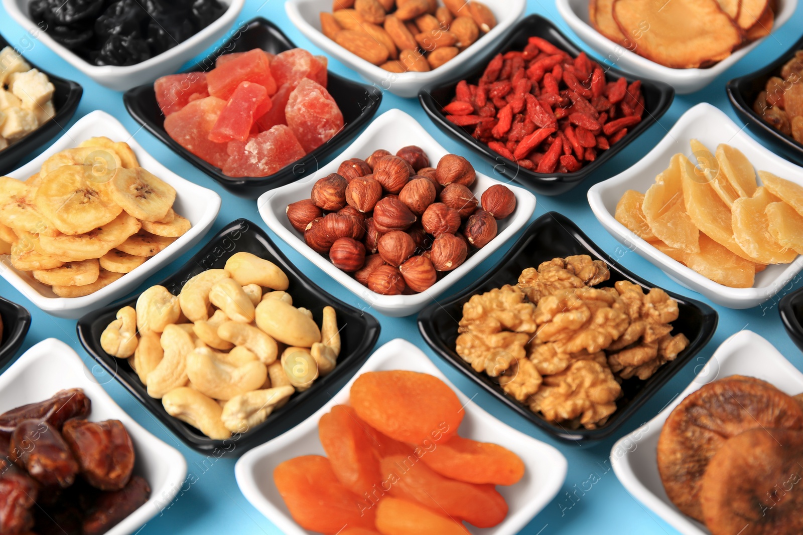 Photo of Bowls with dried fruits and nuts on light blue background