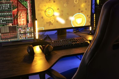 Playing video games. Computer monitor, keyboard and headphones on table indoors