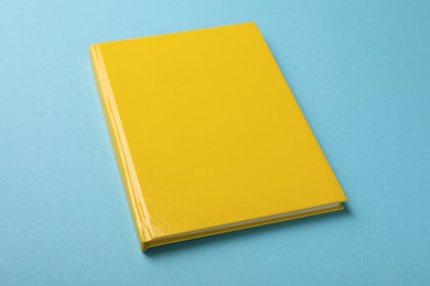 Photo of New yellow planner on light blue background