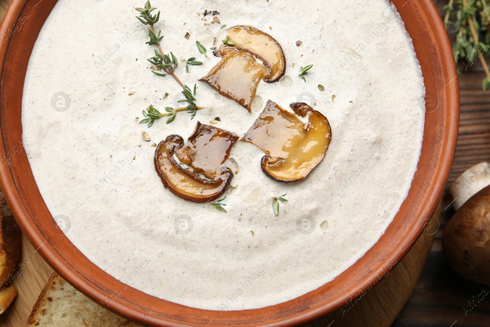 Photo of Fresh homemade mushroom soup in ceramic bowl on wooden table, top view