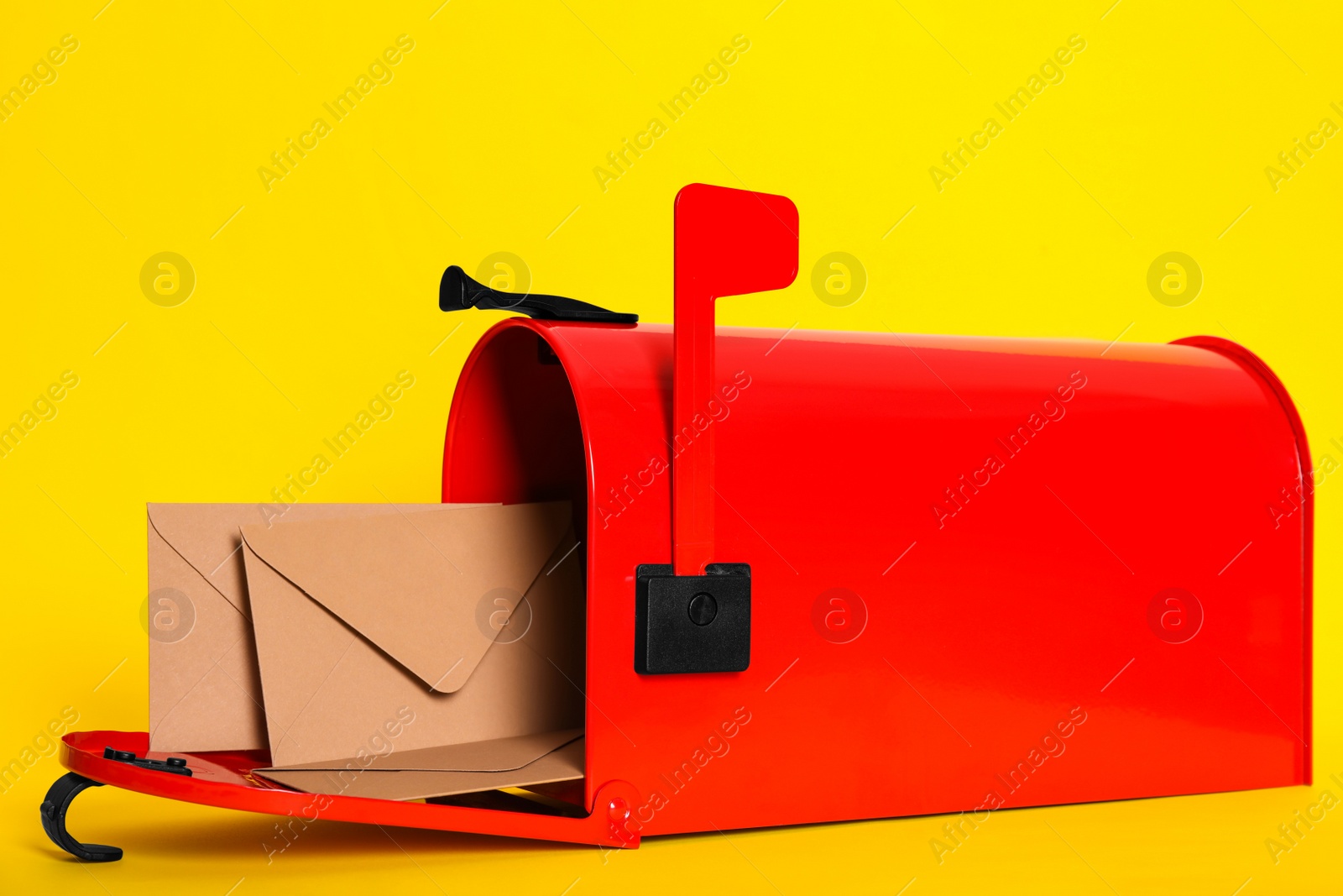 Photo of Open red letter box with envelopes on yellow background, closeup