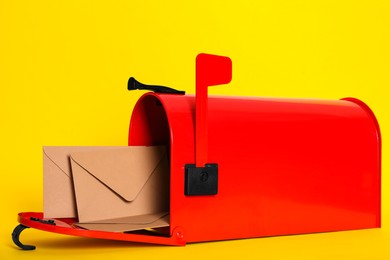 Open red letter box with envelopes on yellow background, closeup