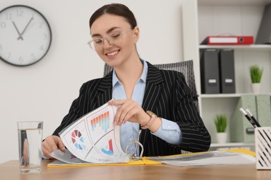 Photo of Businesswoman working with charts at wooden table in office