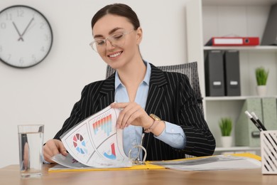 Businesswoman working with charts at wooden table in office