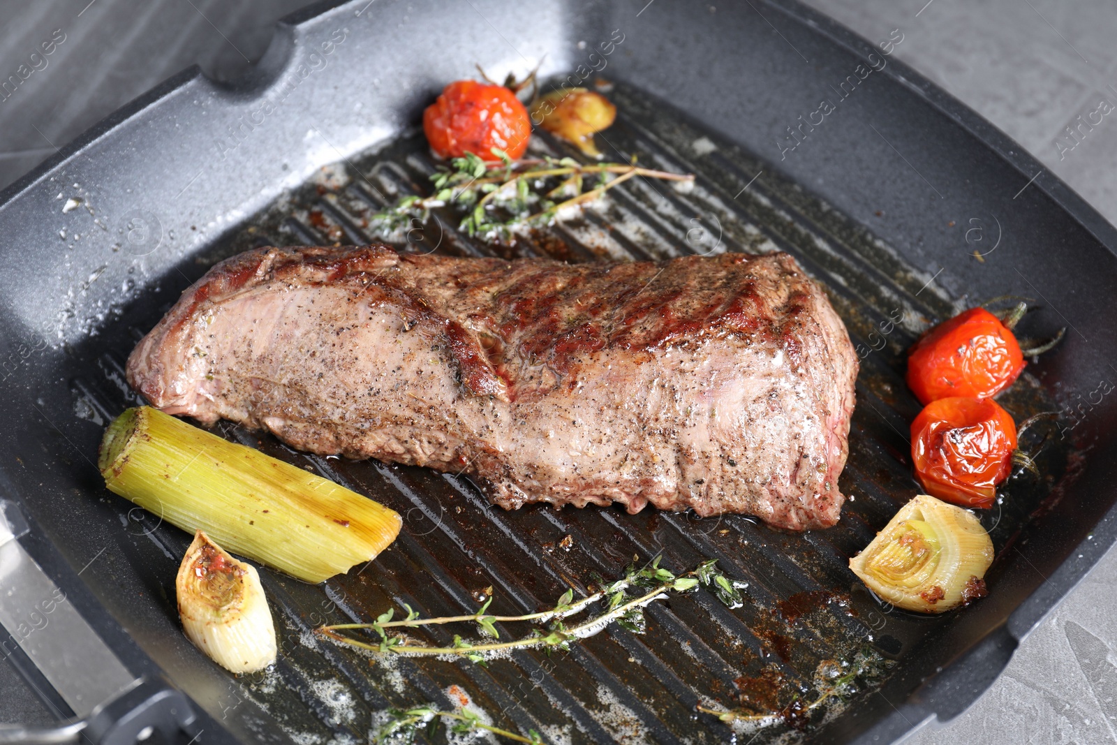 Photo of Delicious grilled beef meat and vegetables in pan on table, closeup