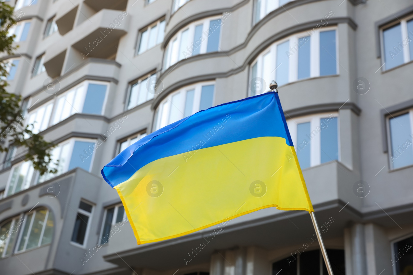 Photo of National flag of Ukraine fluttering near building on sunny day