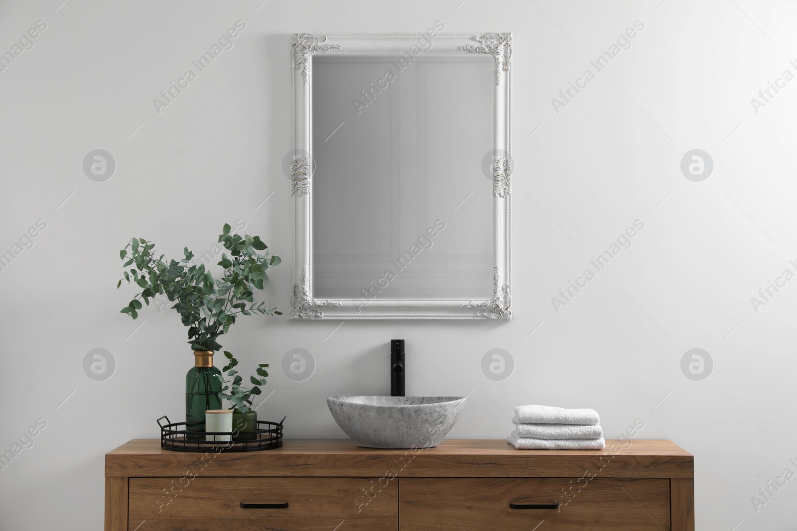 Photo of Modern bathroom interior with stylish mirror, eucalyptus branches, vessel sink and wooden vanity