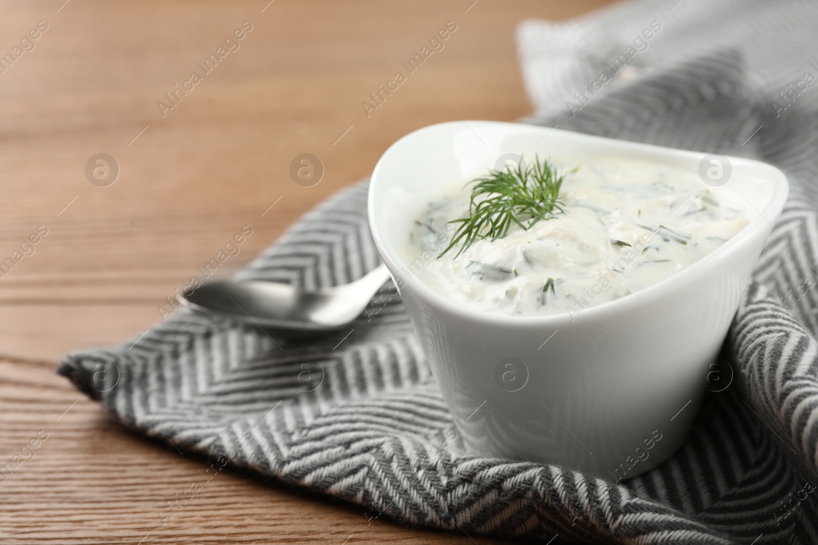 Photo of Cucumber sauce with spoon on wooden background, space for text. Traditional Tzatziki