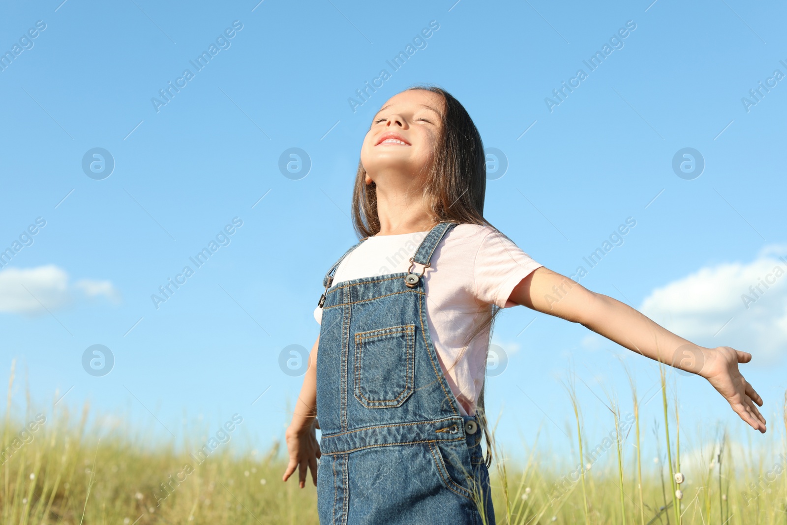 Photo of Cute little girl outdoors on sunny day. Child spending time in nature