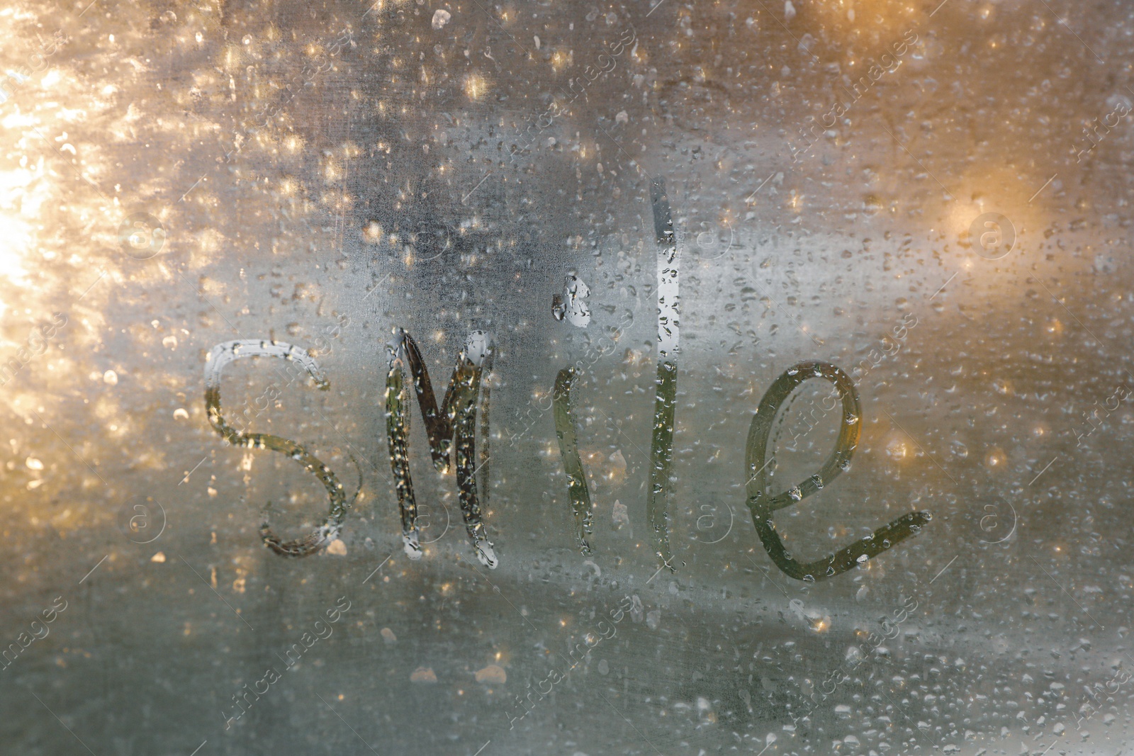 Photo of Word Smile written on foggy window. Rainy weather