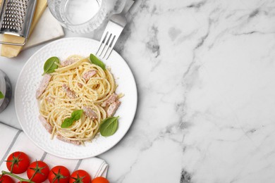 Photo of Plate of tasty pasta Carbonara with basil leaves on white marble table, flat lay. Space for text