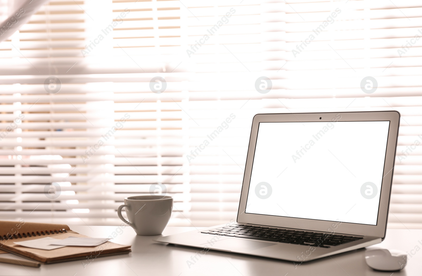 Photo of Laptop on desk near window in office. Comfortable workplace