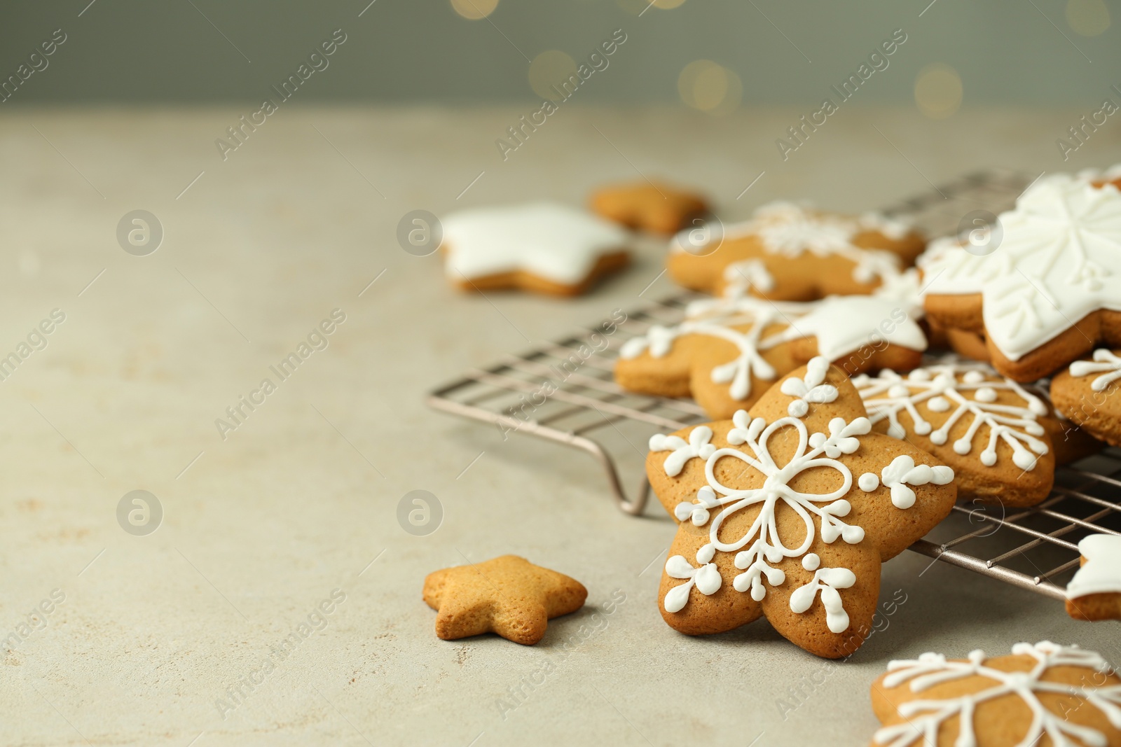 Photo of Tasty Christmas cookies with icing on table against blurred lights. Space for text