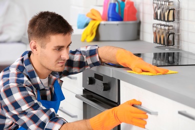Photo of Man cleaning kitchen counter with rag in house