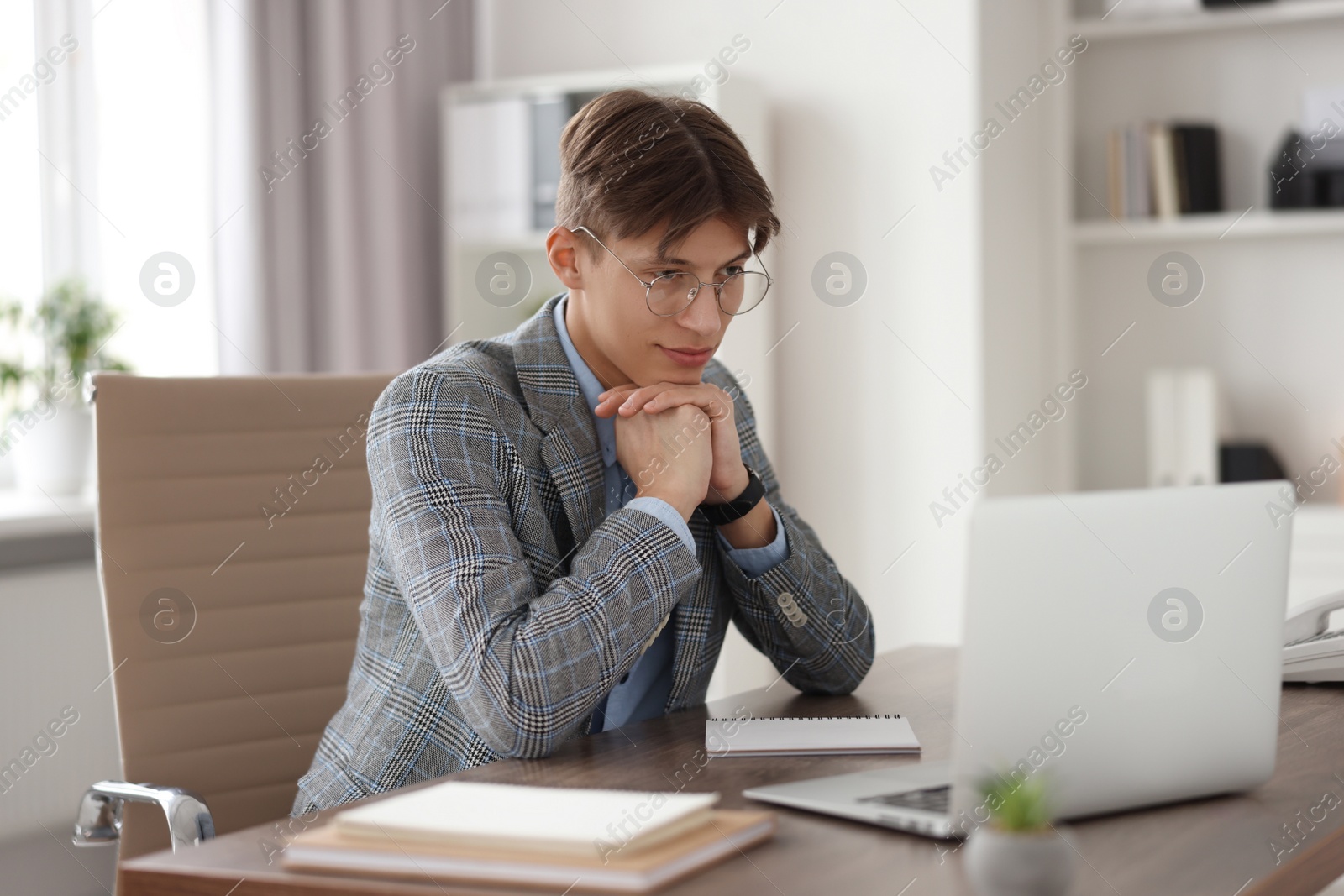 Photo of Man watching webinar at wooden table in office