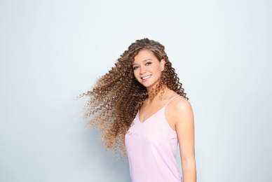 Portrait of beautiful young woman with shiny wavy hair on color background