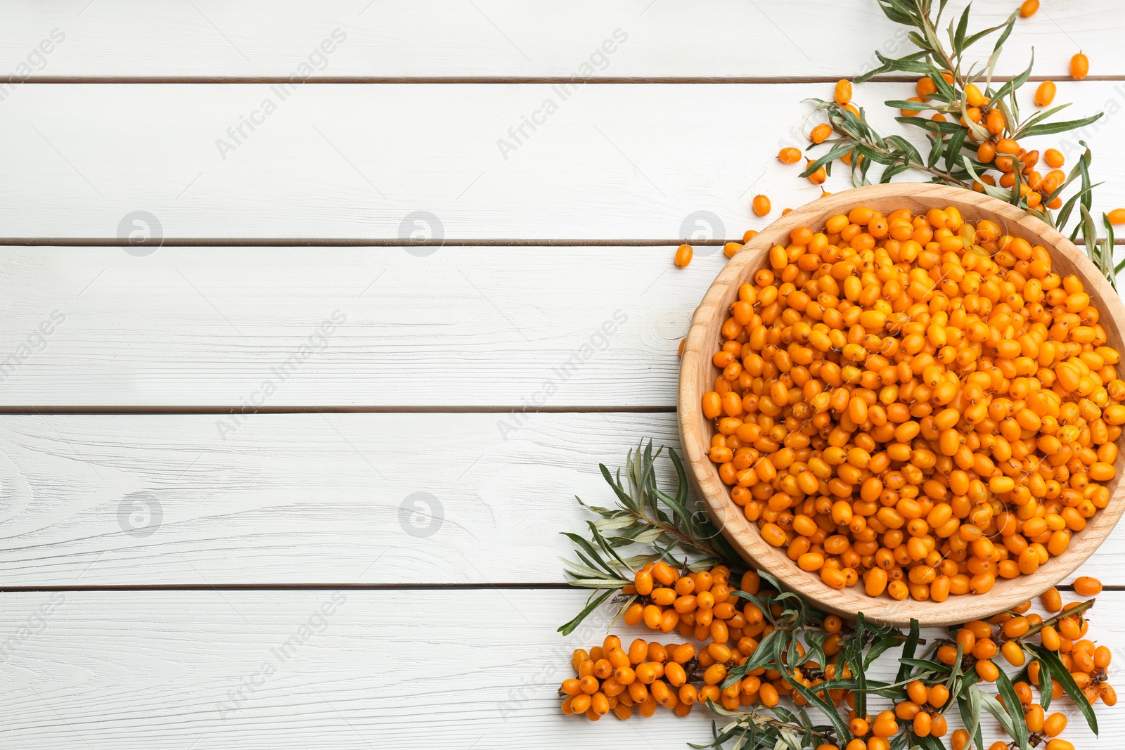 Photo of Fresh ripe sea buckthorn on white wooden table, flat lay. Space for text