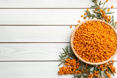 Photo of Fresh ripe sea buckthorn on white wooden table, flat lay. Space for text