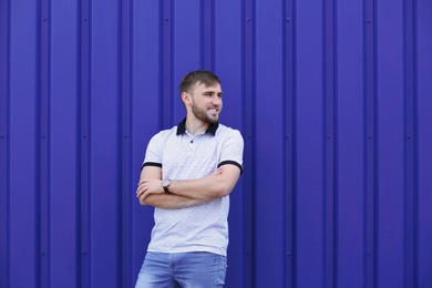 Photo of Young hipster man in stylish jeans posing near color wall