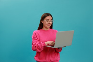 Young woman with modern laptop on light blue background