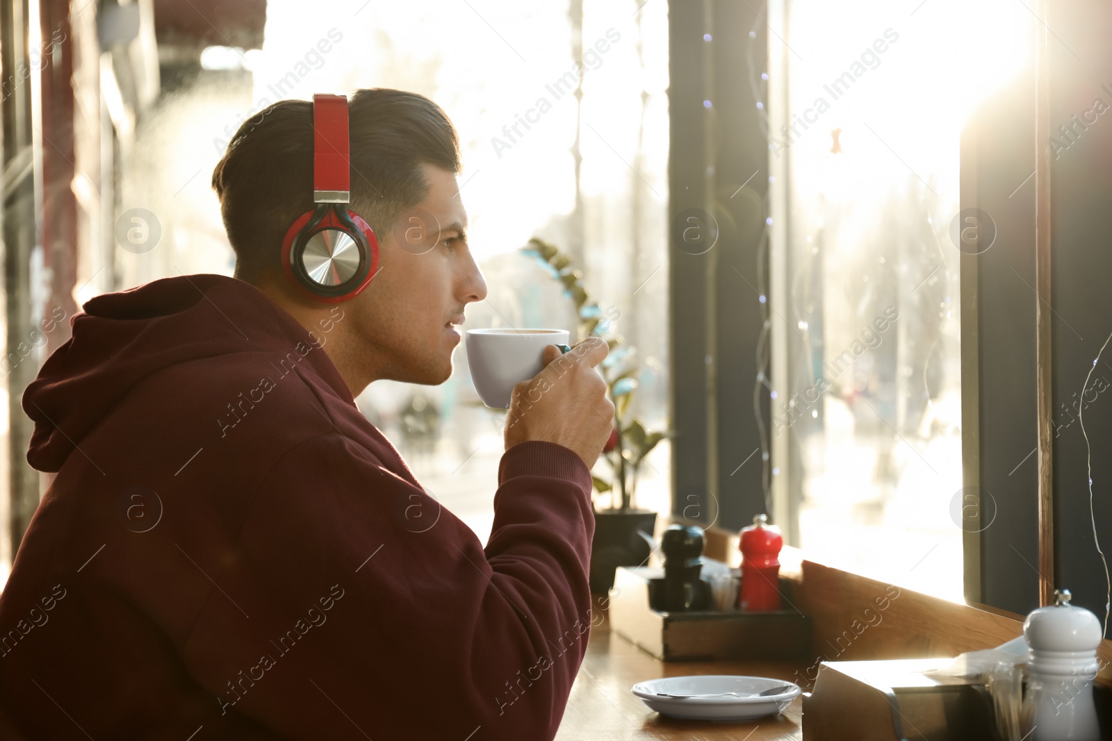 Photo of Man listening to audiobook at table in cafe