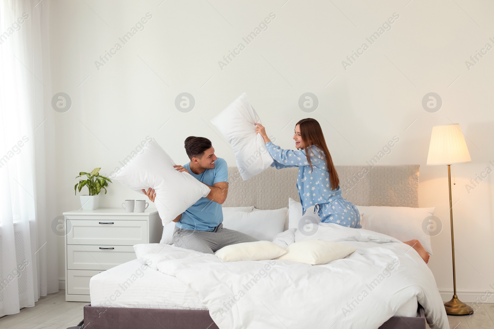 Photo of Happy couple having pillow fight in bedroom