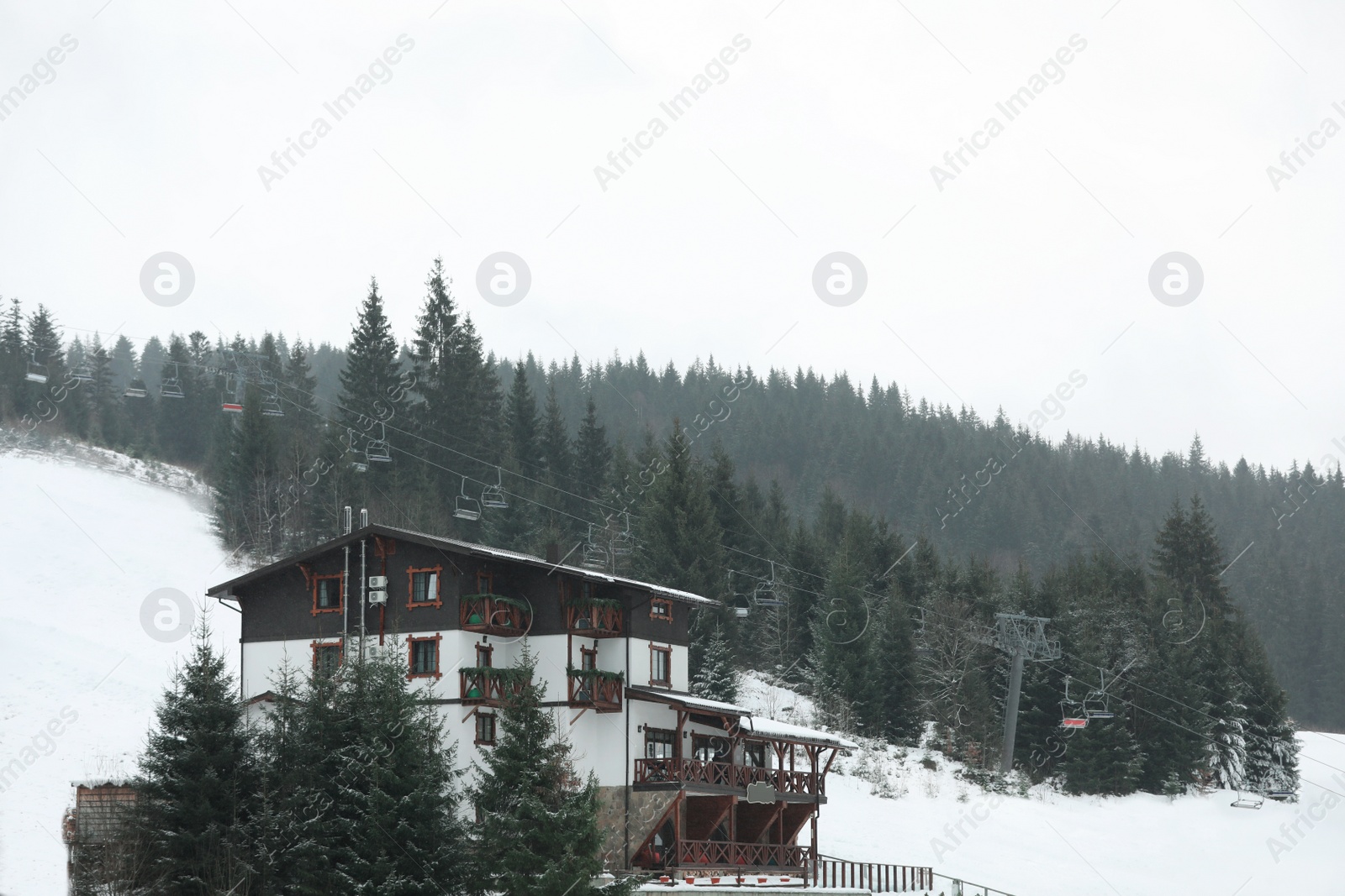 Photo of Beautiful view of ski resort with chairlift on snowy day. Winter vacation