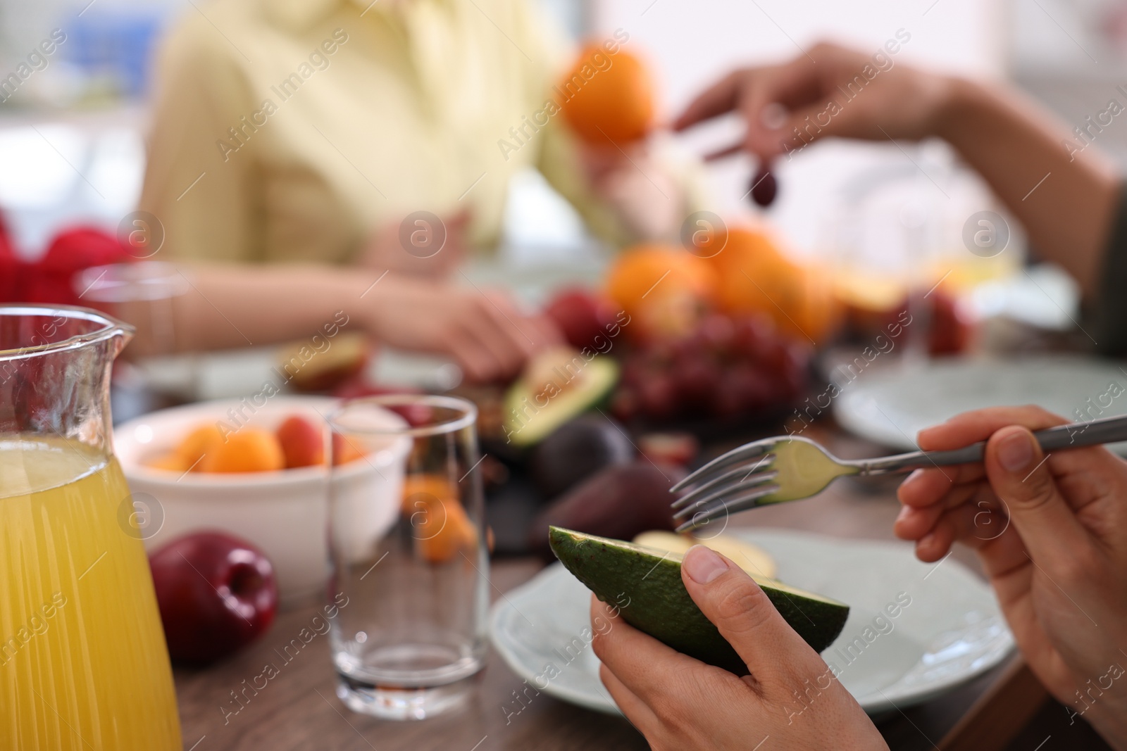 Photo of Friends eating vegetarian food at table indoors, closeup