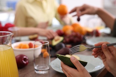 Photo of Friends eating vegetarian food at table indoors, closeup