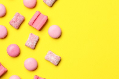 Pink bubble gums on yellow background, flat lay. Space for text