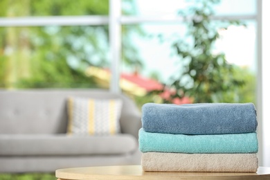 Stack of folded clean soft towels on table indoors. Space for text