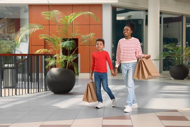Photo of Family shopping. Happy mother and son with purchases in mall