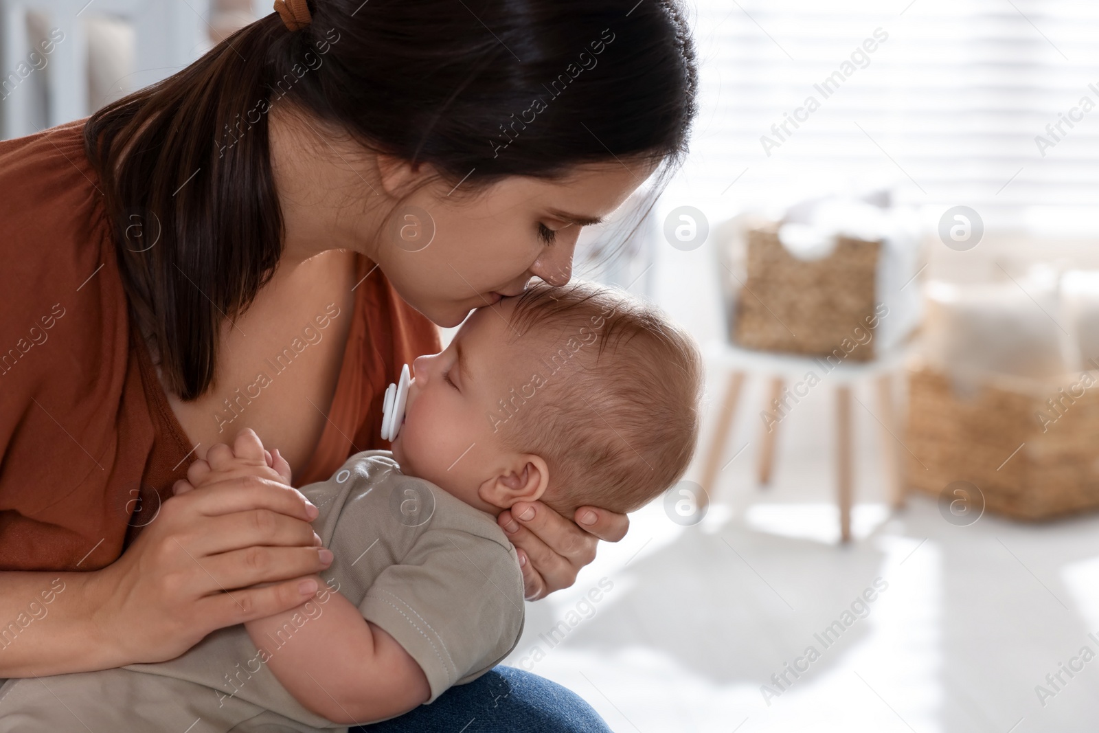 Photo of Happy young mother with her sleeping baby at home. Space for text