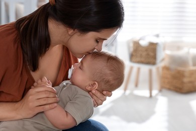 Photo of Happy young mother with her sleeping baby at home. Space for text