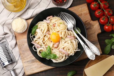 Photo of Delicious pasta Carbonara with egg yolk on wooden table, flat lay