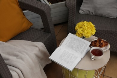 Photo of Different pillows, blanket, book and beautiful chrysanthemum flowers on garden furniture outdoors